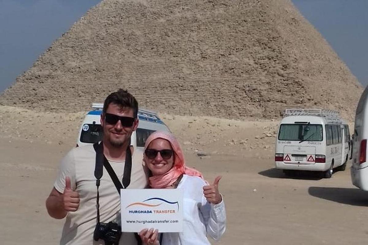 muž a žena držící ceduli před pyramidou