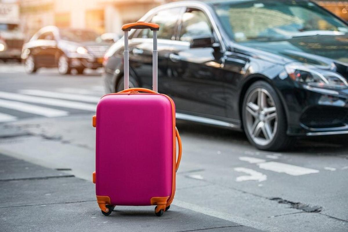 uma mala rosa parada na rua ao lado de um carro