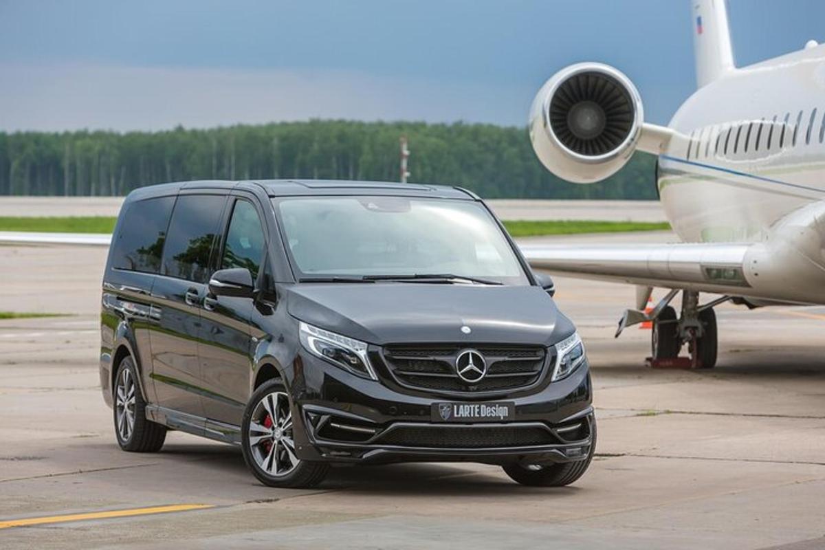 van Acedes estacionada na pista de um aeroporto ao lado de um avião