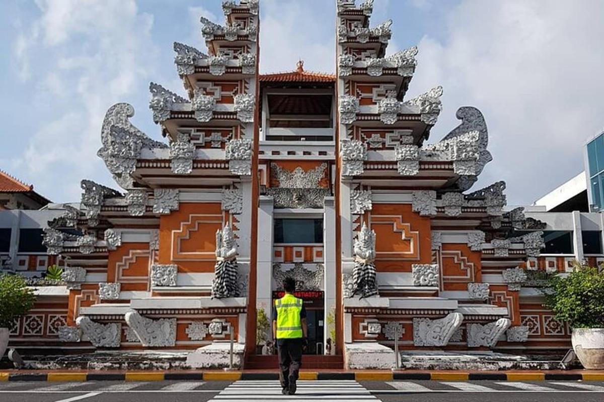 seorang lelaki berjaket kuning berdiri di hadapan sebuah bangunan