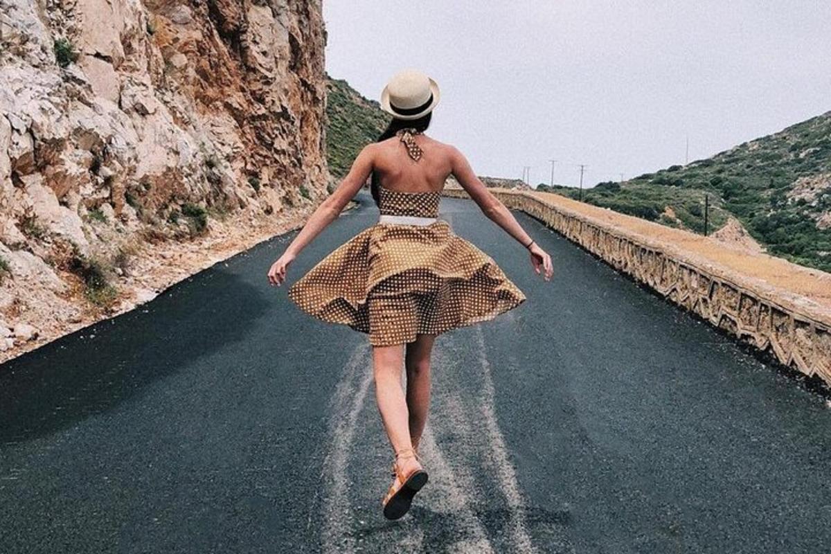 uma mulher de vestido caminhando por uma estrada