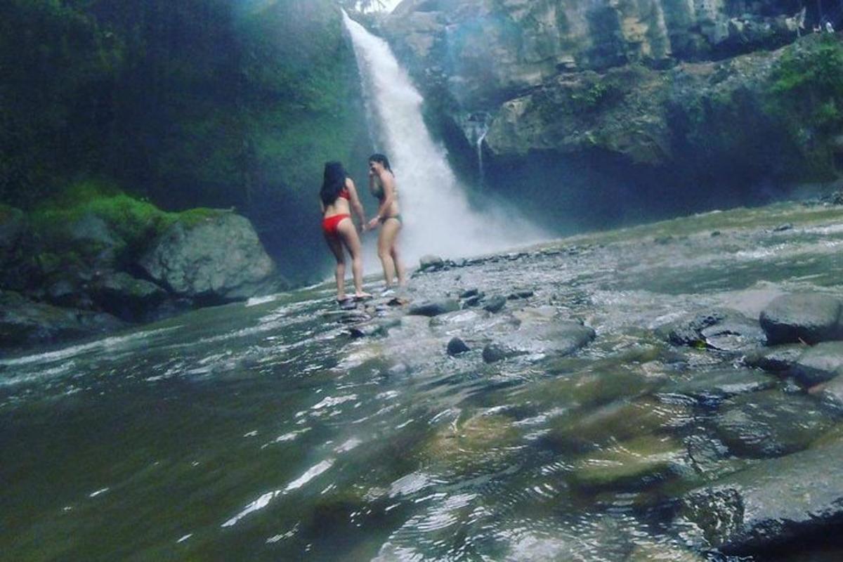 due donne in costume da bagno in piedi davanti a una cascata