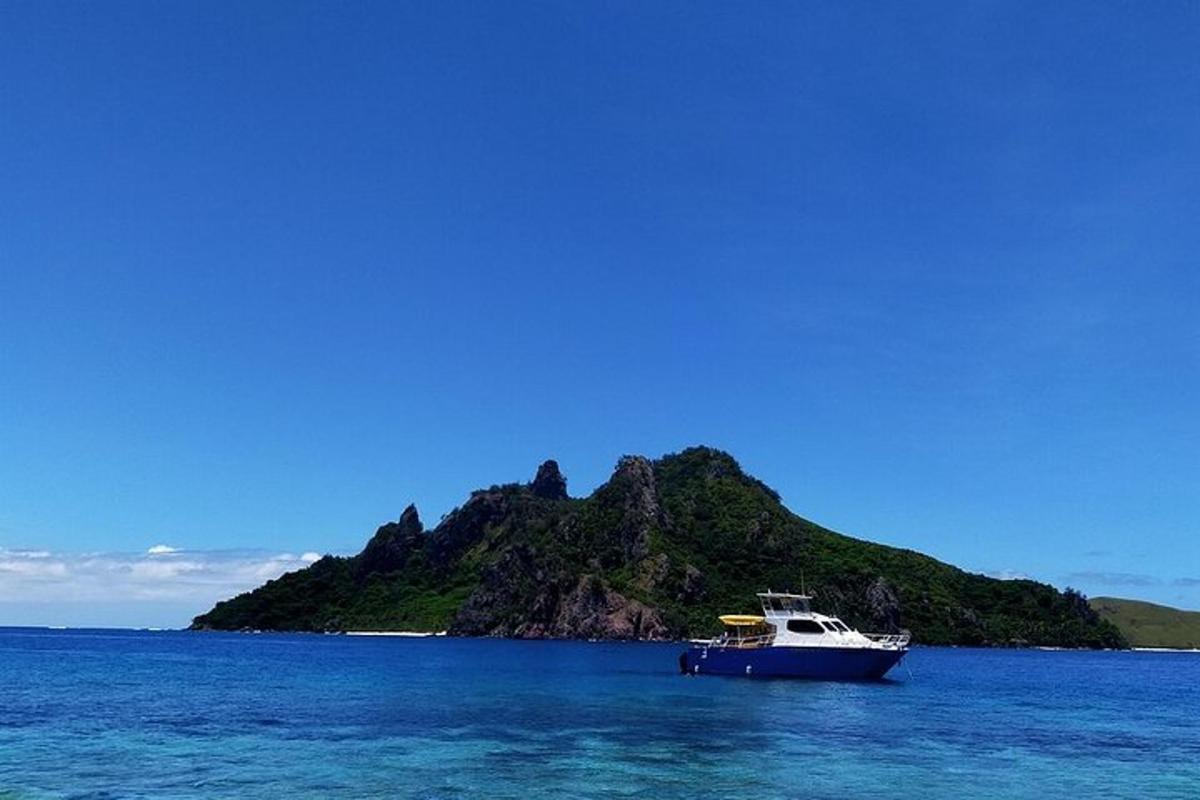 a boat in the water near an island in the ocean