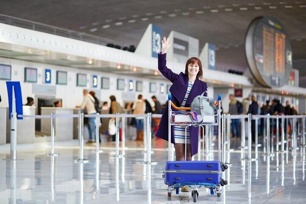 Una mujer parada con la mano en alto en un aeropuerto.