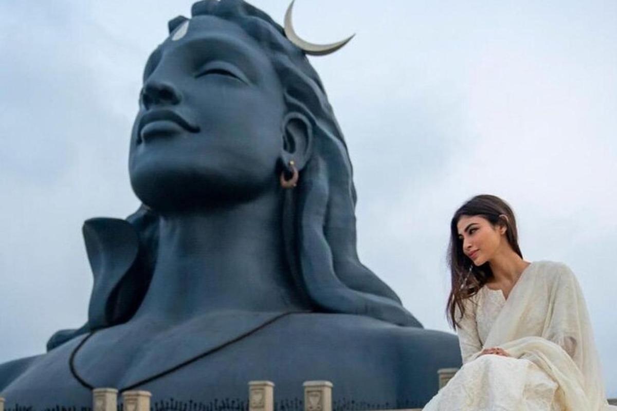 a woman sitting in front of a statue