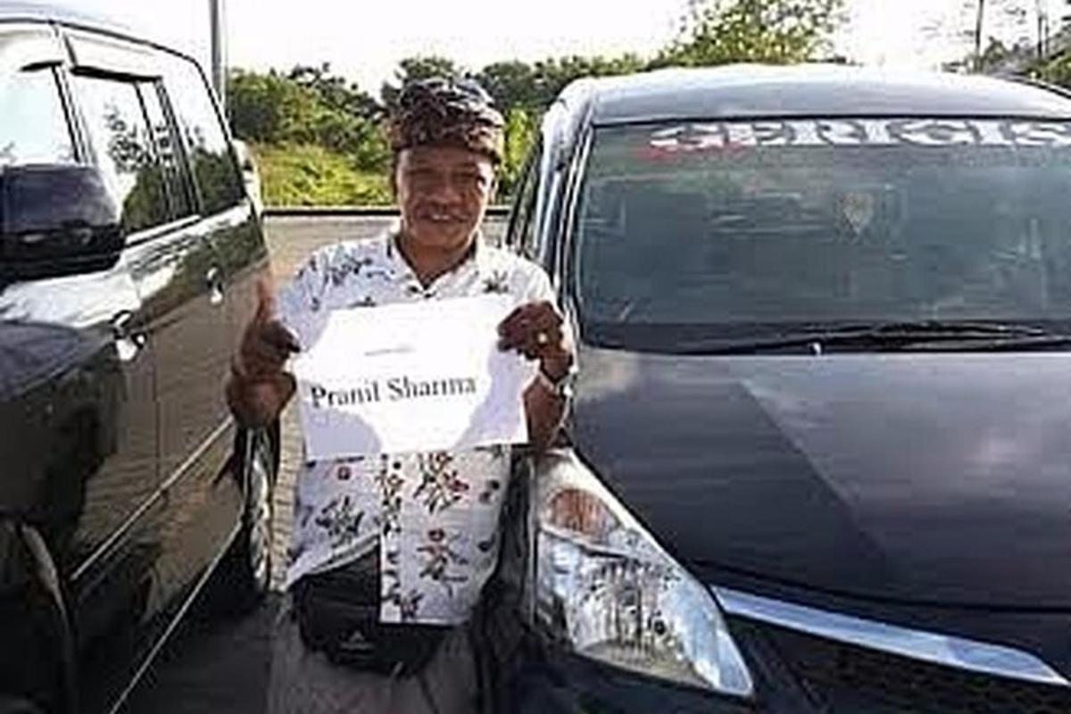 um homem segurando uma placa na frente de um carro