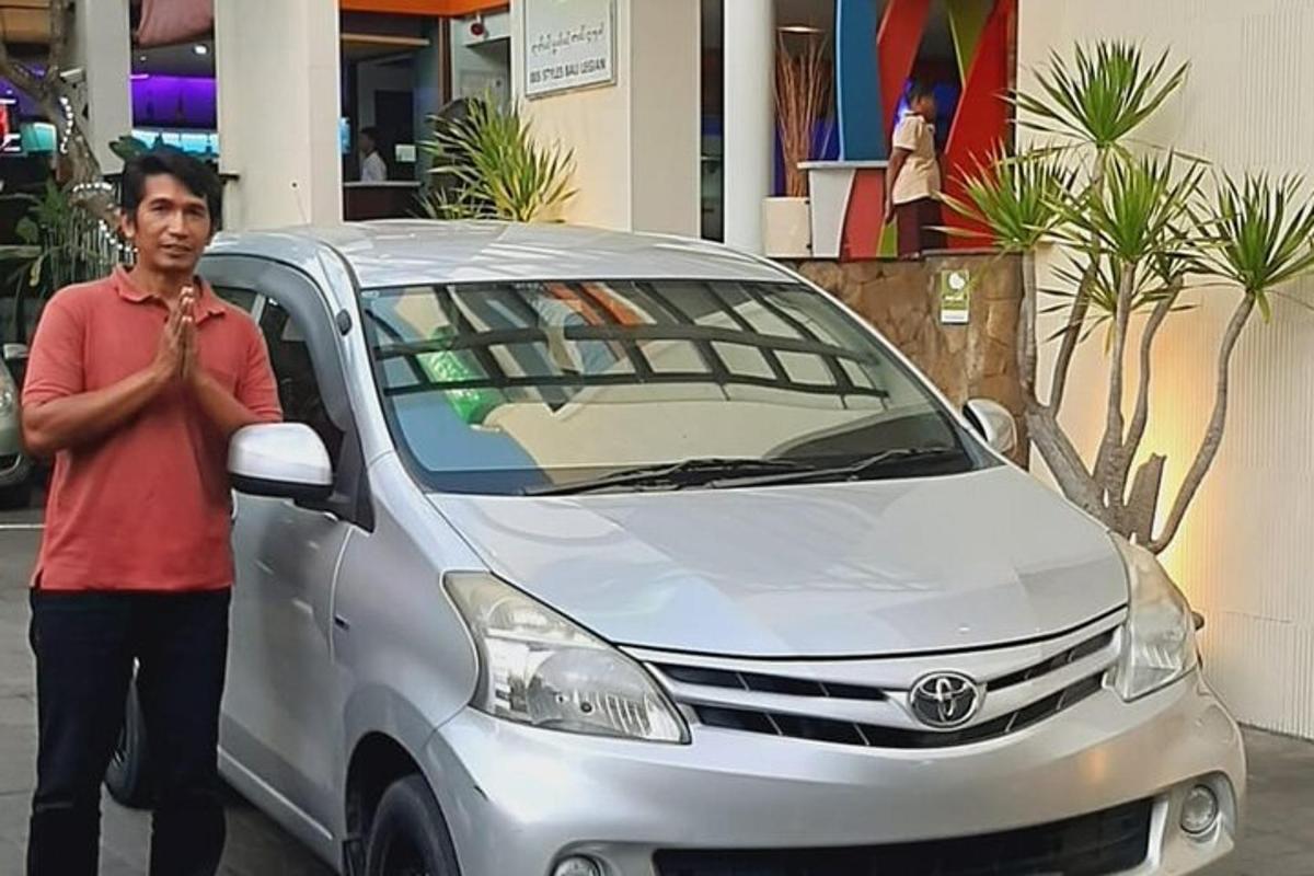 um homem parado ao lado de um carro prateado