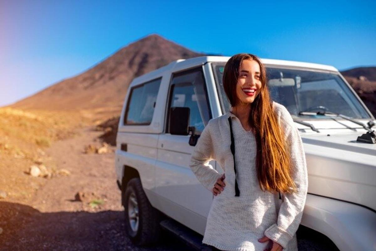 uma mulher parada ao lado de uma van branca no deserto