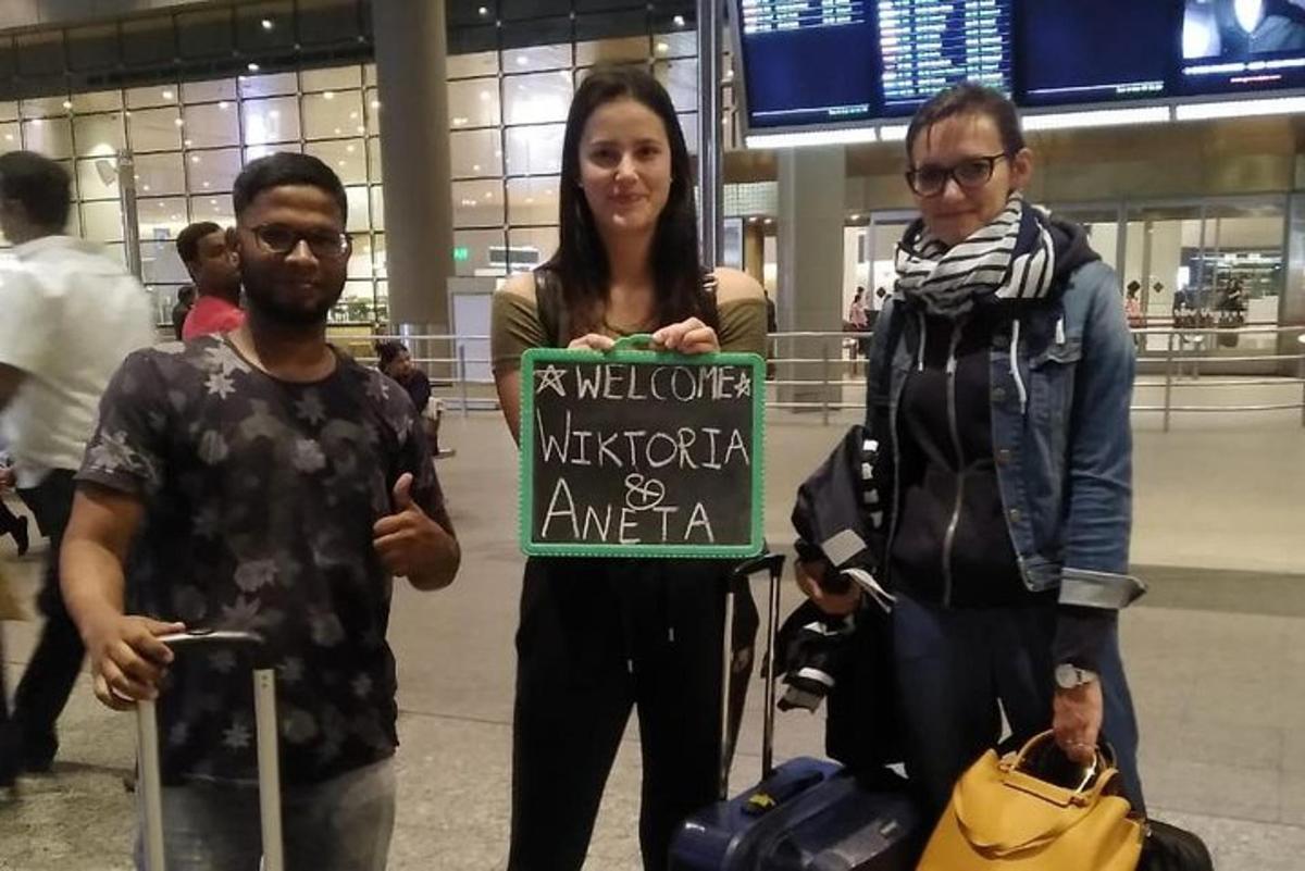 three people standing in an airport holding a sign