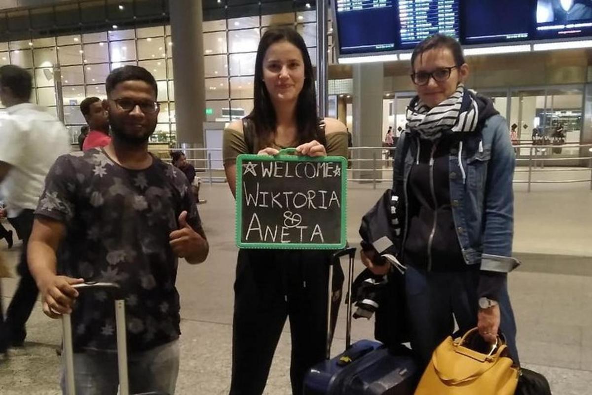 three people standing in an airport holding a sign
