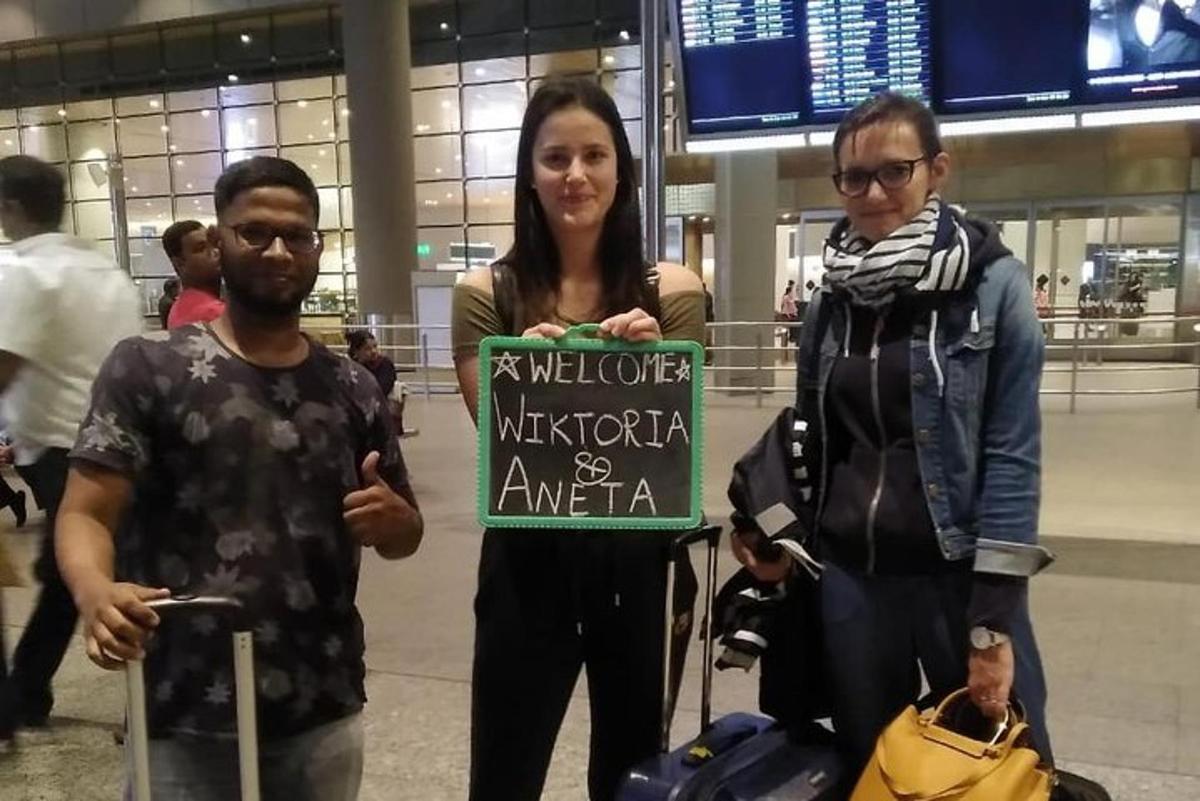 drei Personen stehen in einem Flughafen und halten ein Schild