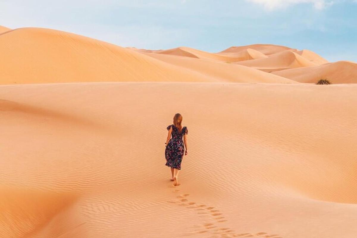 a woman walking on a sand dune in the desert