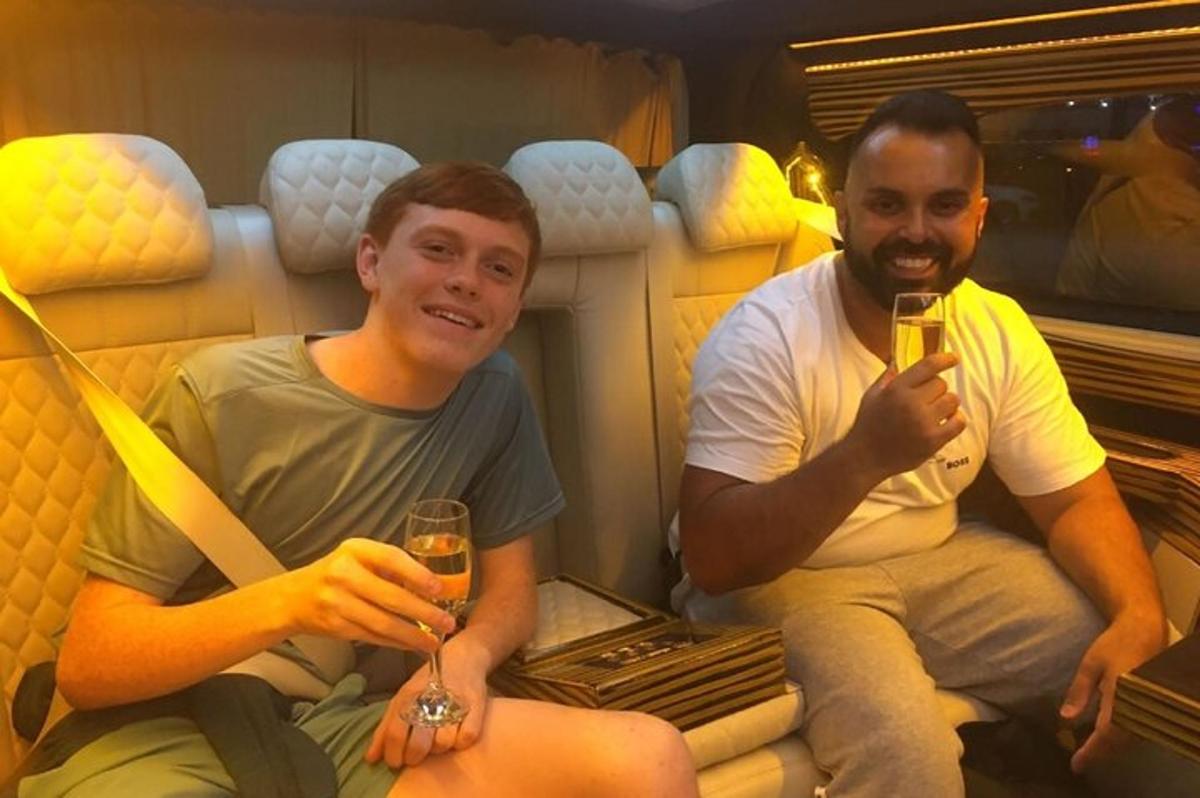 two men sitting on a couch with glasses of wine