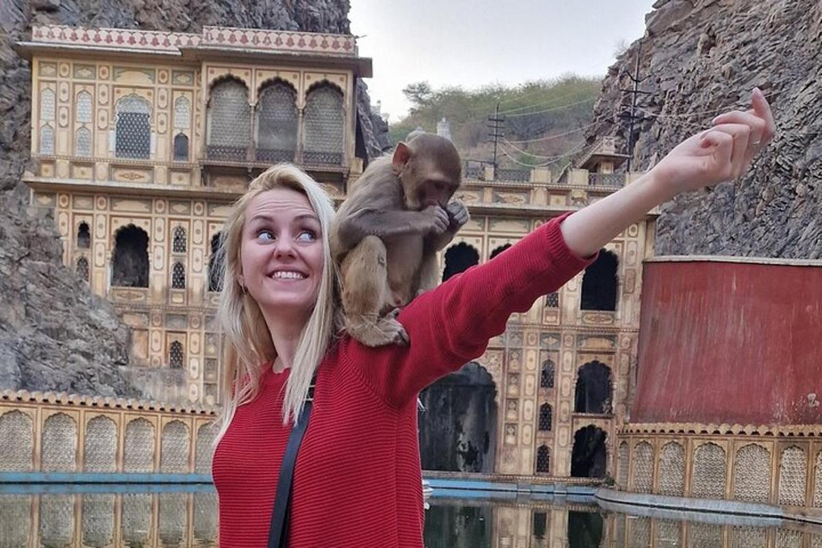 a woman holding a monkey on her arm in front of a building