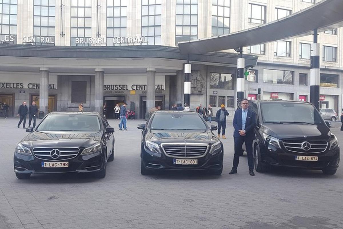 muž stojící mezi dvěma auty před budovou