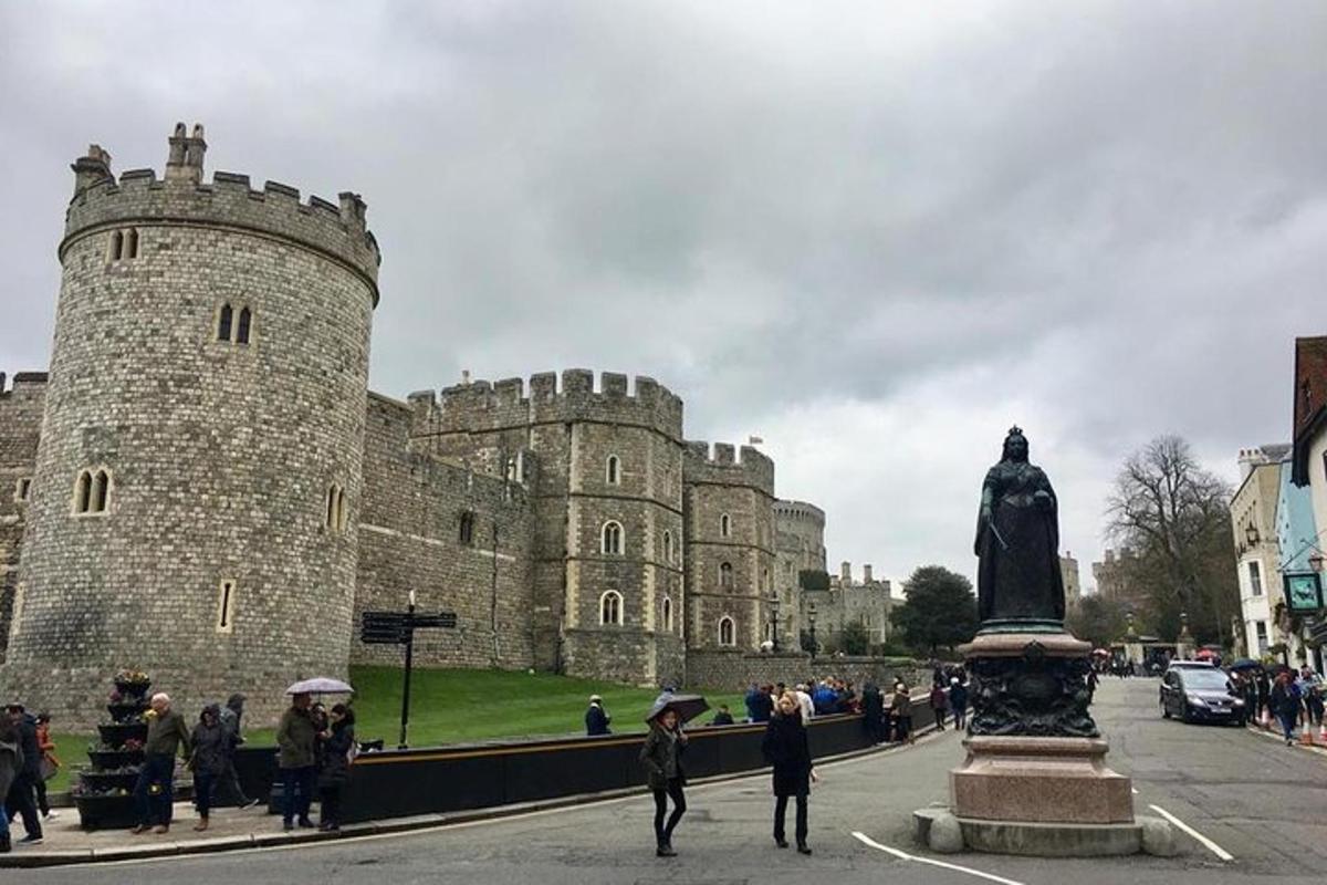 gent amb paraigües caminant davant d'un castell