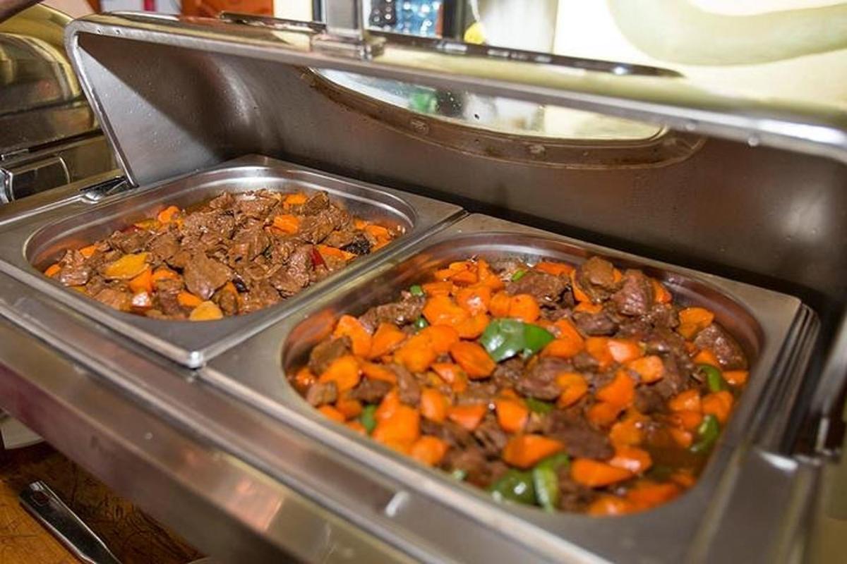 two trays of meat and vegetables in an oven