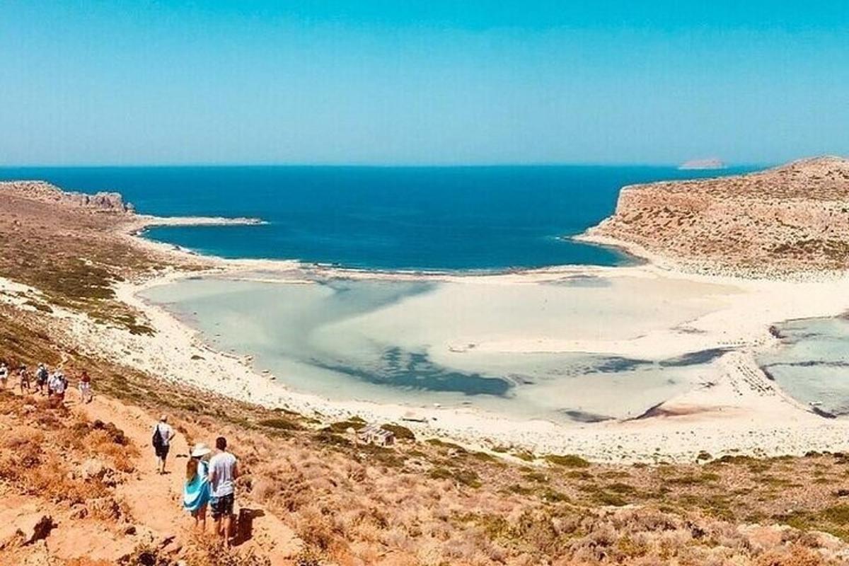 Un grupo de personas caminando por una colina cerca del océano.