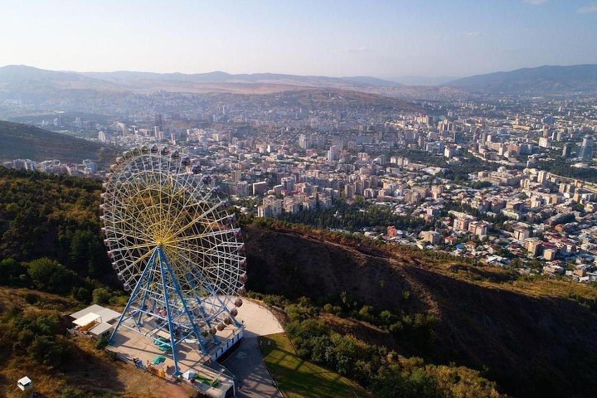 Una noria en la cima de una colina con una ciudad