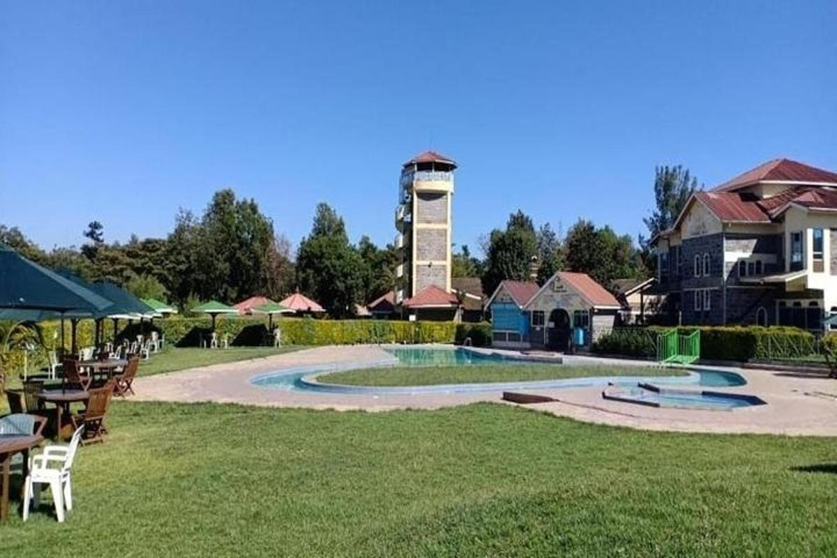 una piscina in un cortile con tavoli e sedie