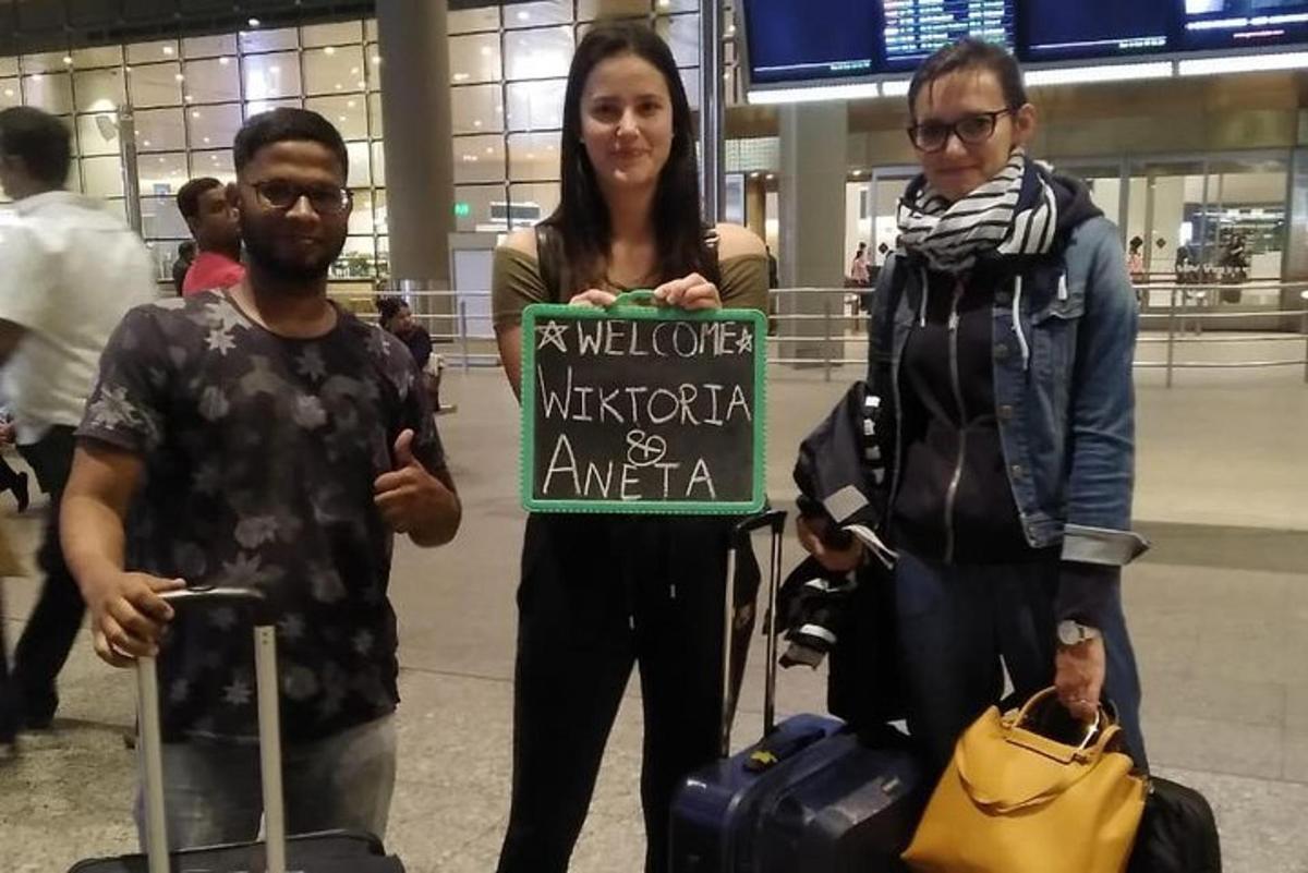 three people standing in an airport holding a sign