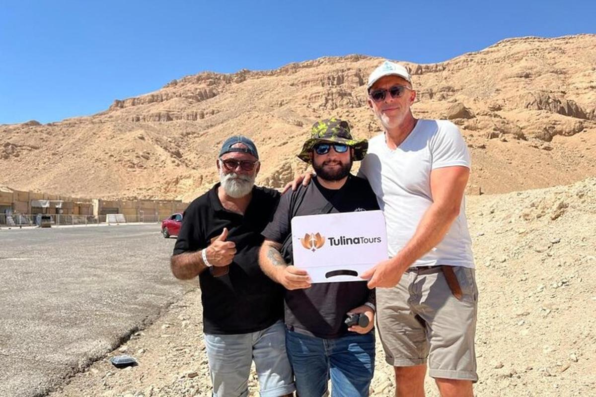 un grup de tres homes sostenint un cartell al desert