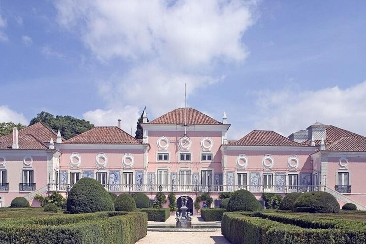 een groot roze gebouw met struiken ervoor