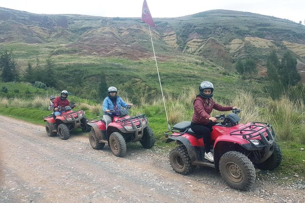 tre persone che guidano quad su una strada sterrata