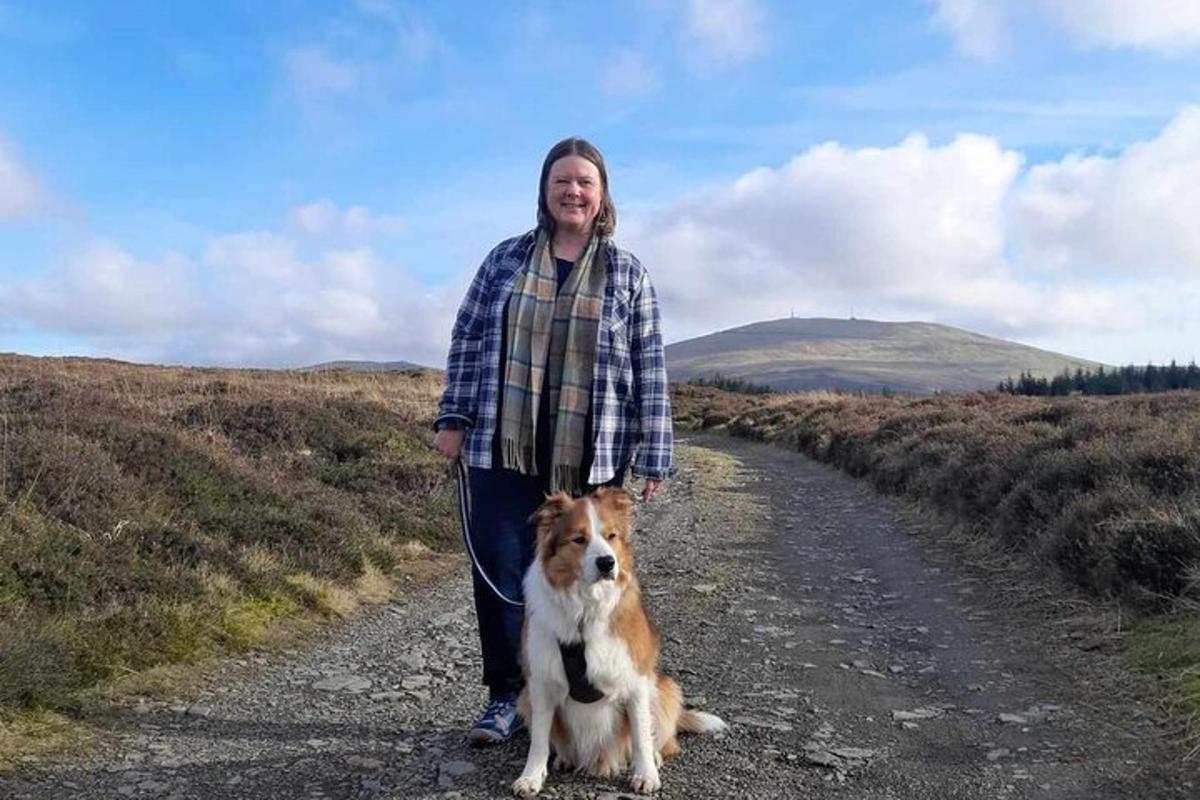 a woman standing next to a dog on a dirt road