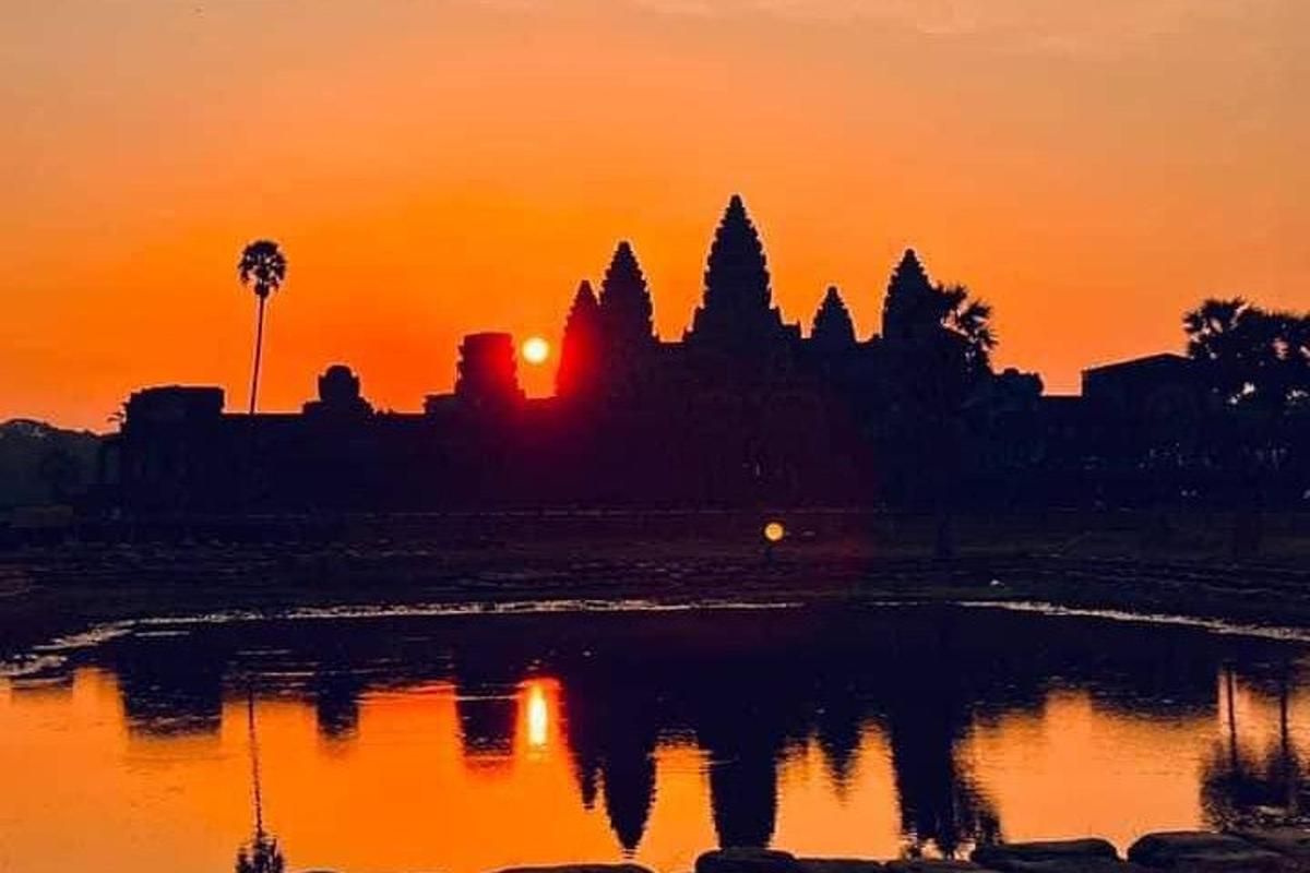 Una puesta de sol con el reflejo de un templo en el agua.