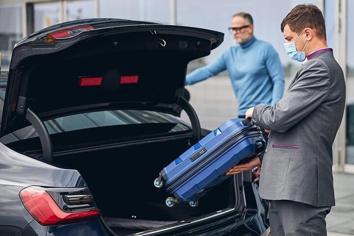 Tveir menn hlaða farangri í skott bíls