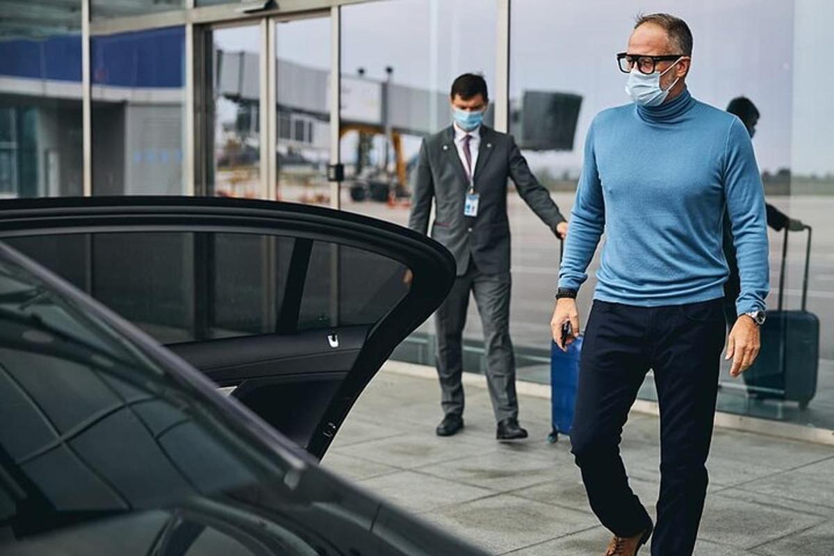 en mann med ansiktsmaske som går ved siden av en bil