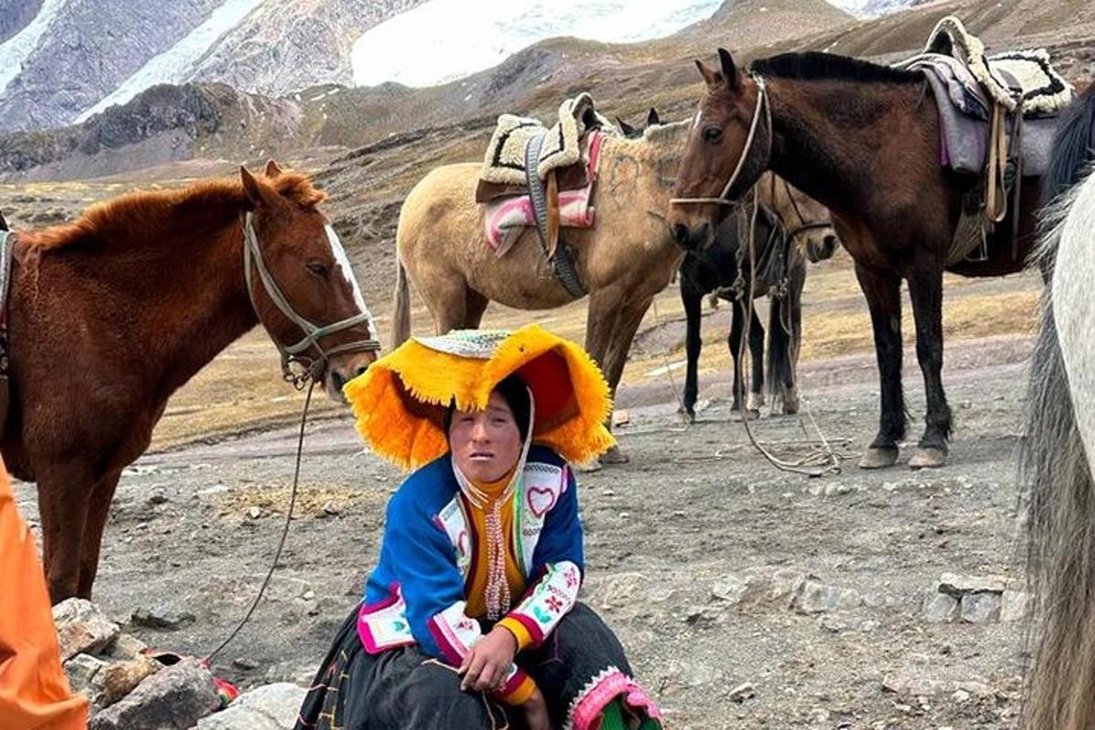 Un niño pequeño sentado frente a un grupo de caballos