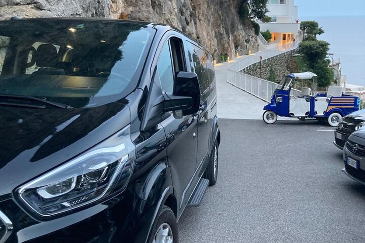 een zwarte bestelwagen geparkeerd op de weg met een golfkarretje