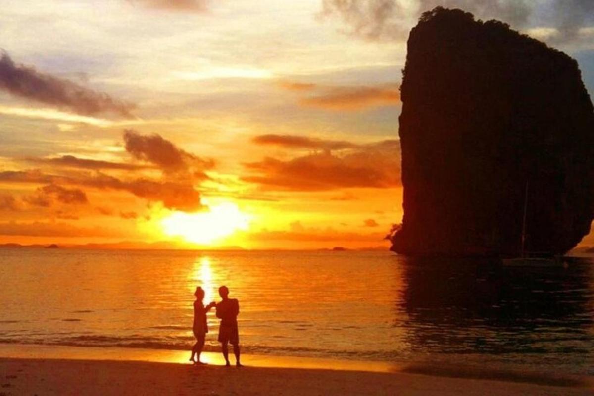 una coppia in piedi sulla spiaggia che guarda il tramonto