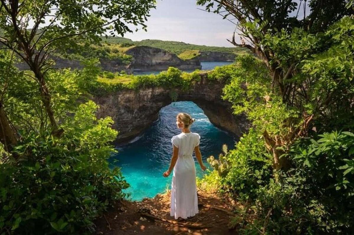 a woman in a white dress standing in front of a bridge