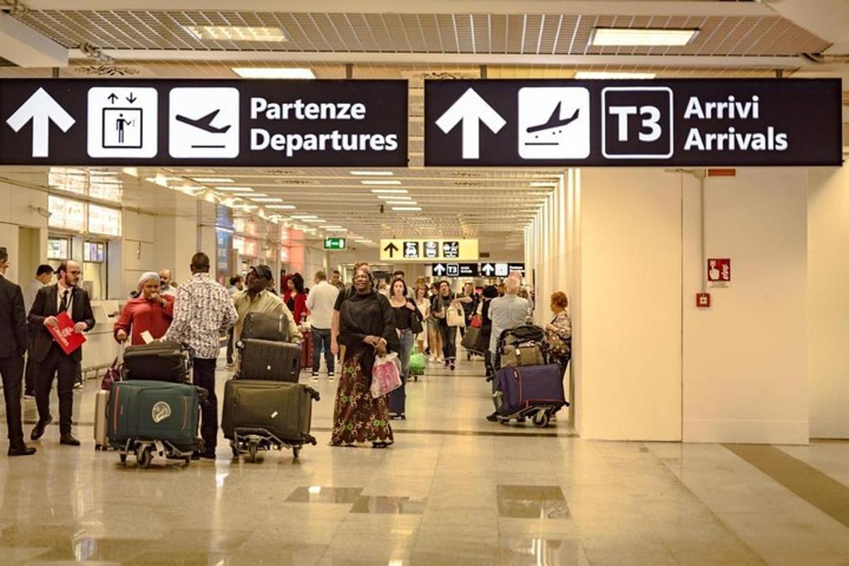 Grupa ludzi idąca przez lotnisko ze swoim bagażem