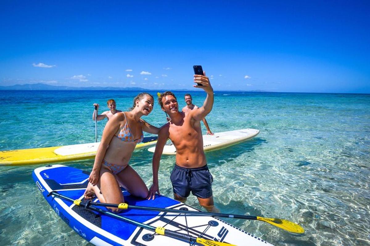 a group of people standing on a paddle board in the ocean