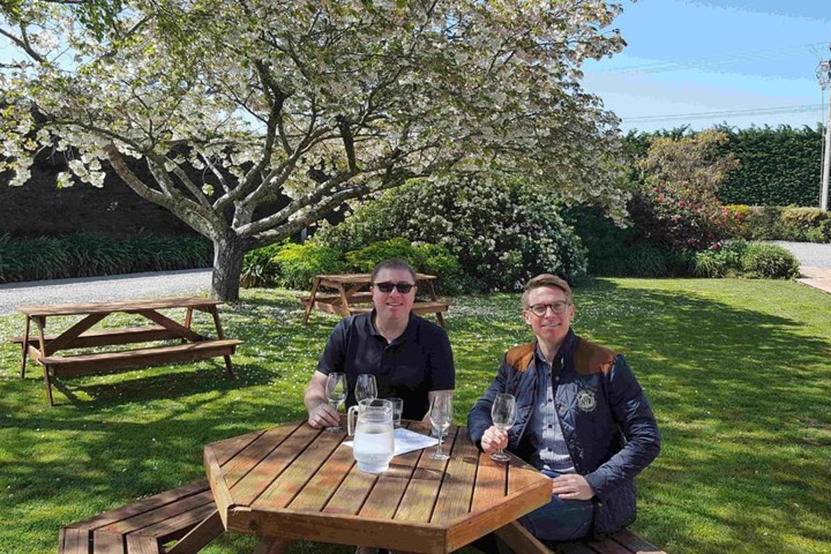 two people sitting at a picnic table with wine glasses