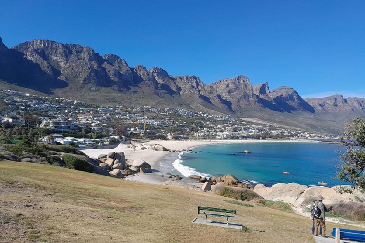 eine Person, die auf einem Hügel steht und auf einen Strand mit Bergen blickt