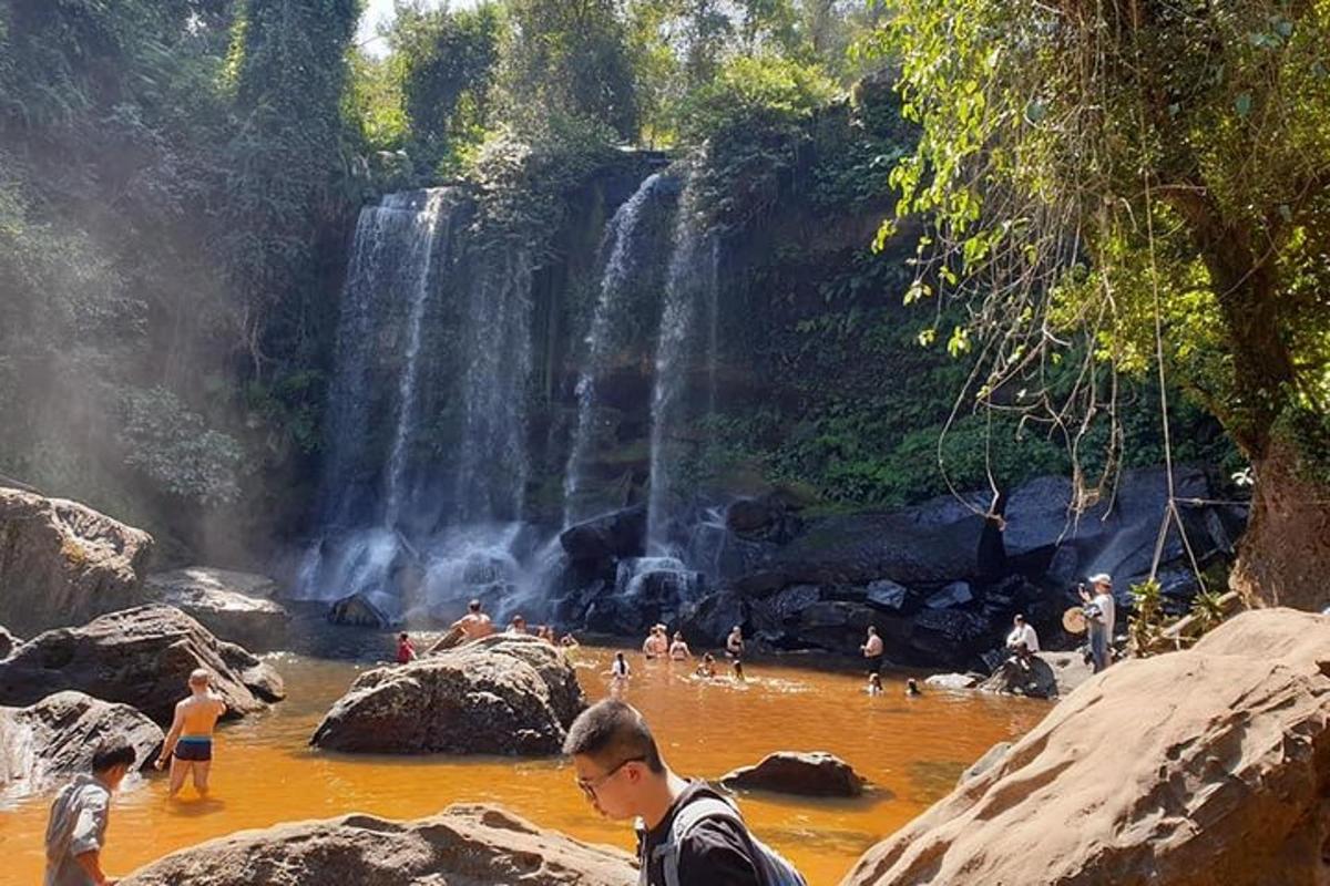 Un grupo de personas en el agua cerca de una cascada.