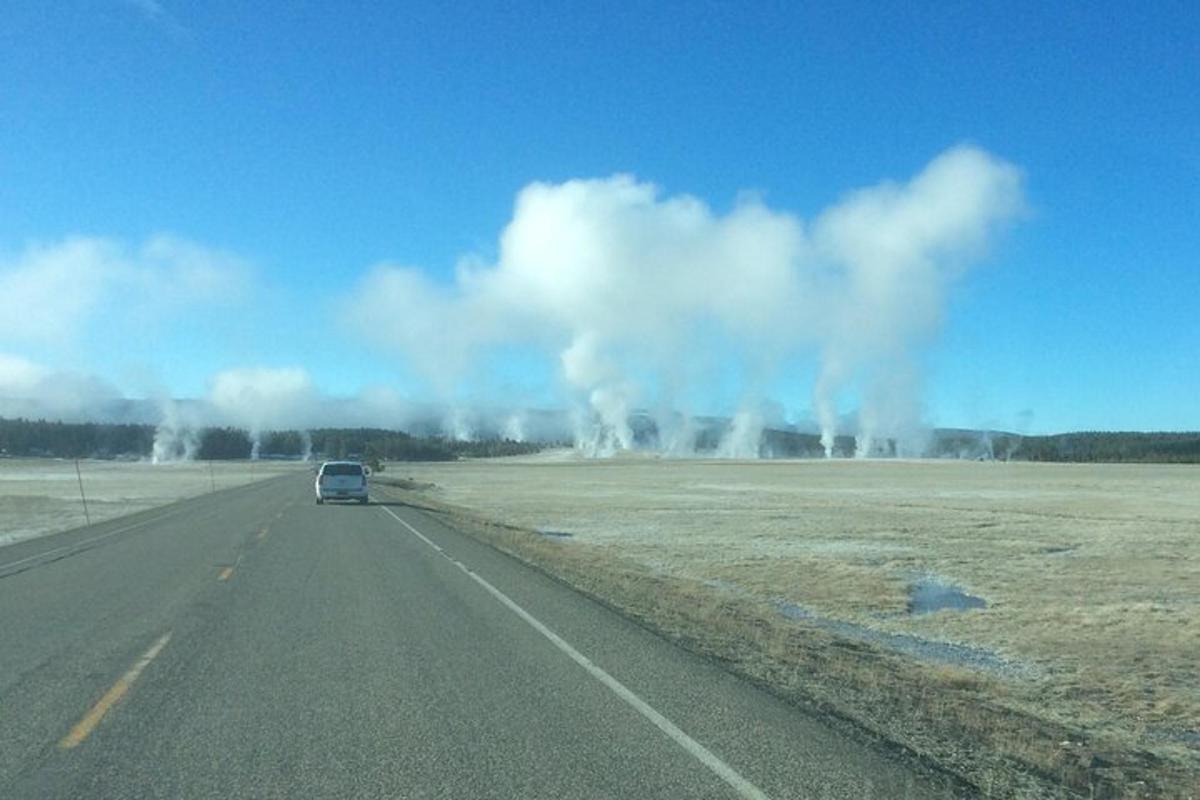 a car driving down a road with smoke in the distance