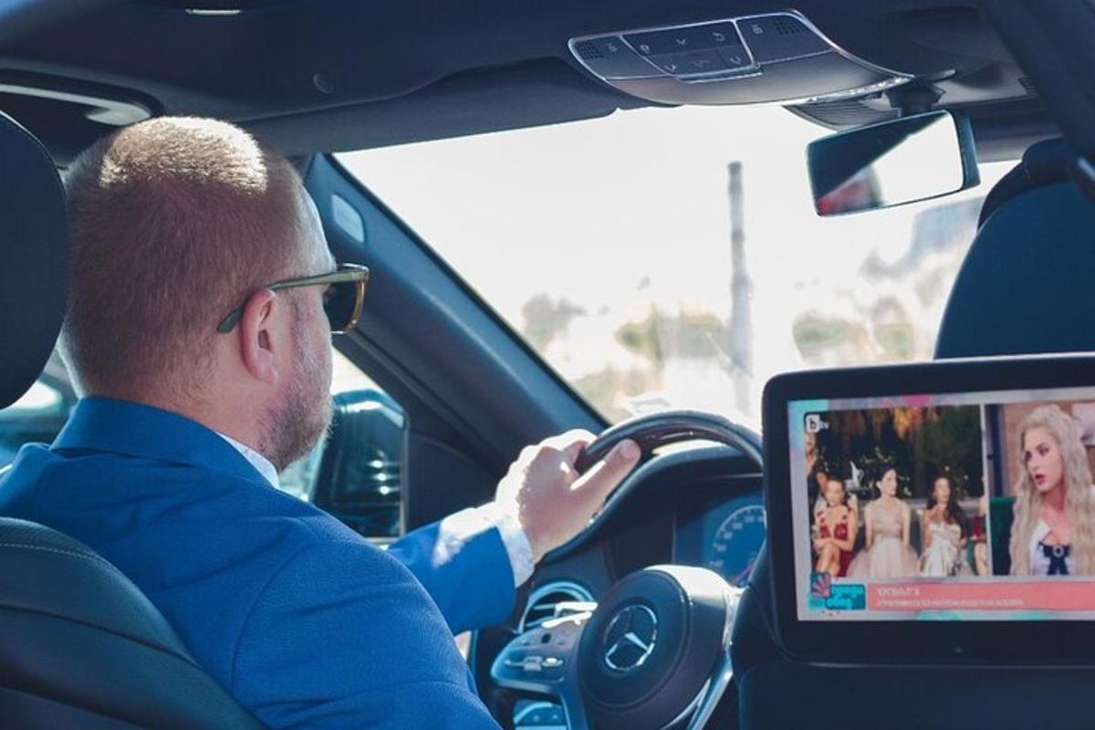 un uomo alla guida di un'auto con un computer sul volante