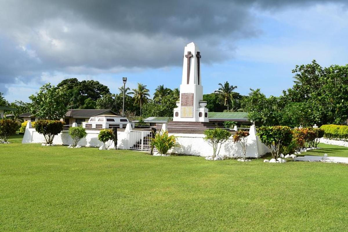 a monument in front of a building with a grass field
