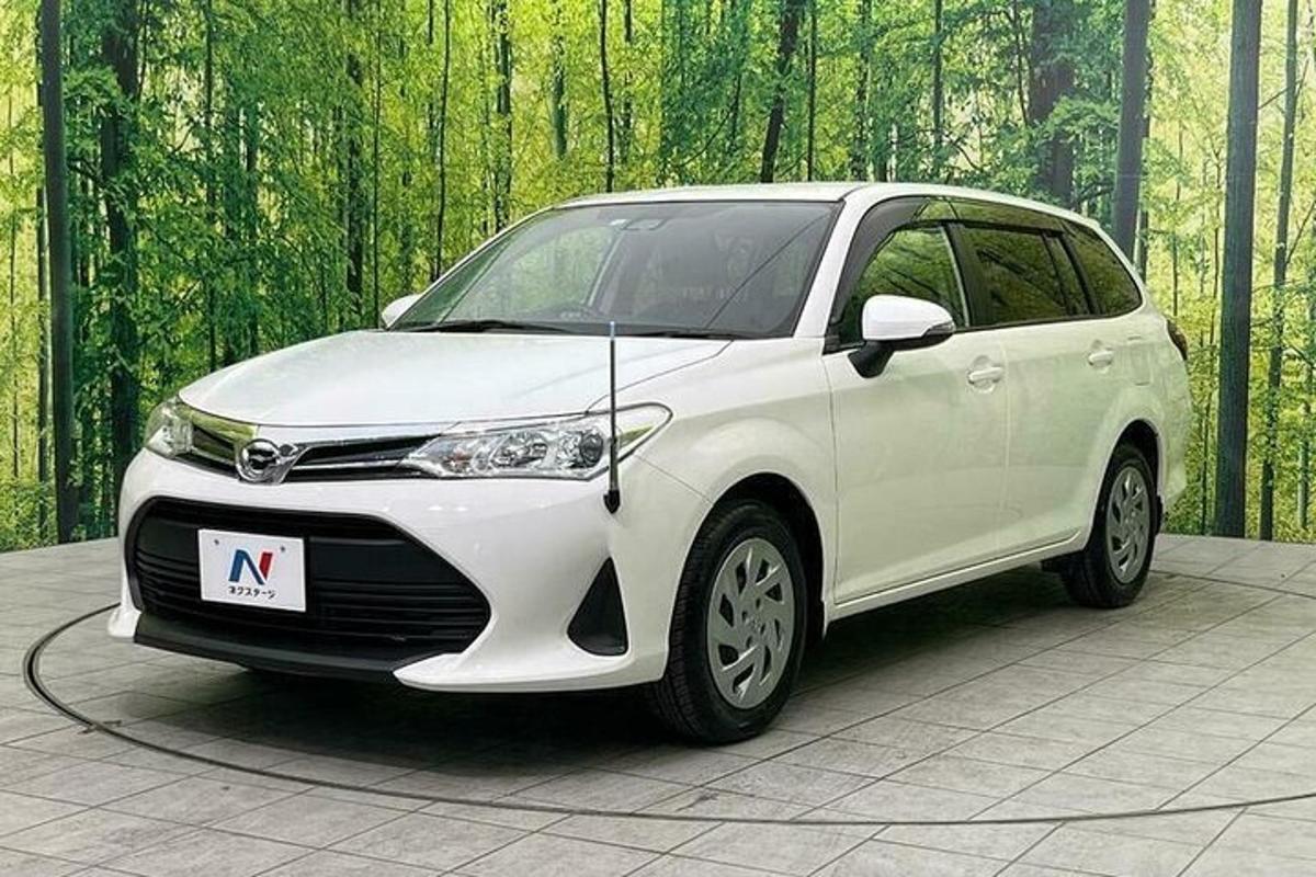 bílé auto zaparkované před lesem