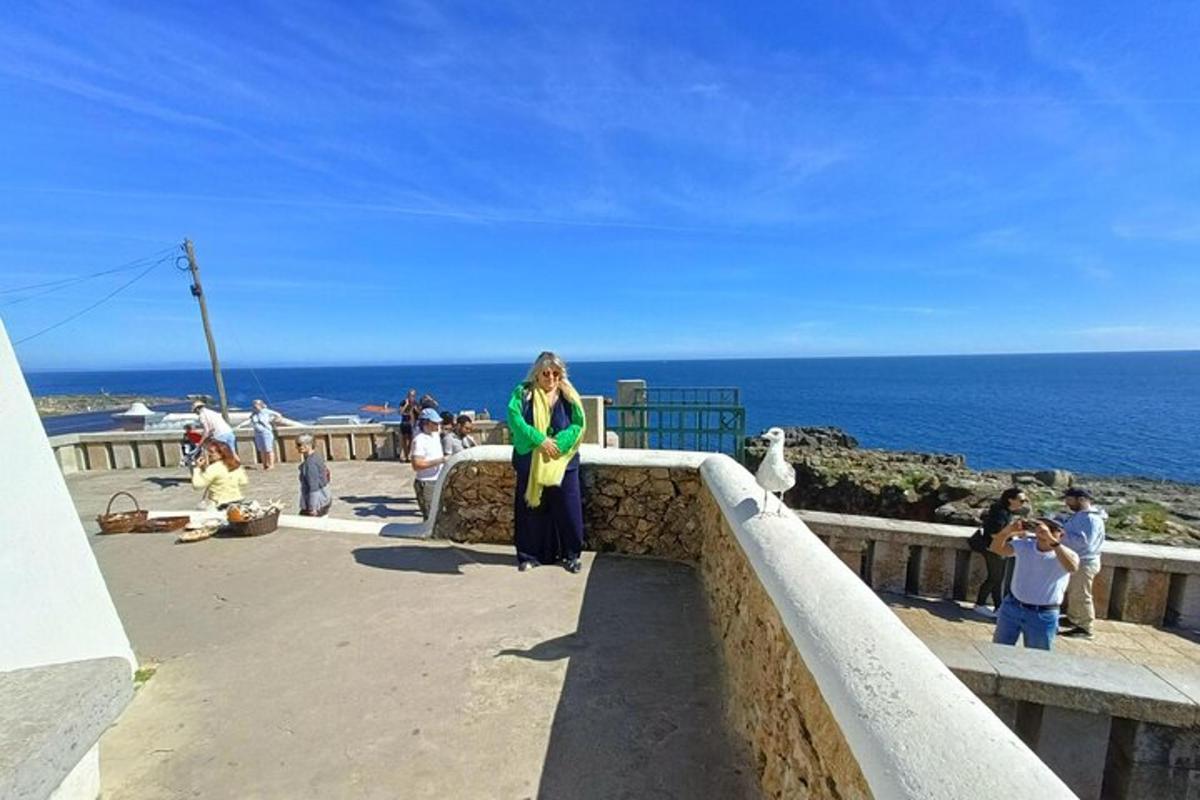 žena stojaca na rímse a pozerajúca sa na oceán