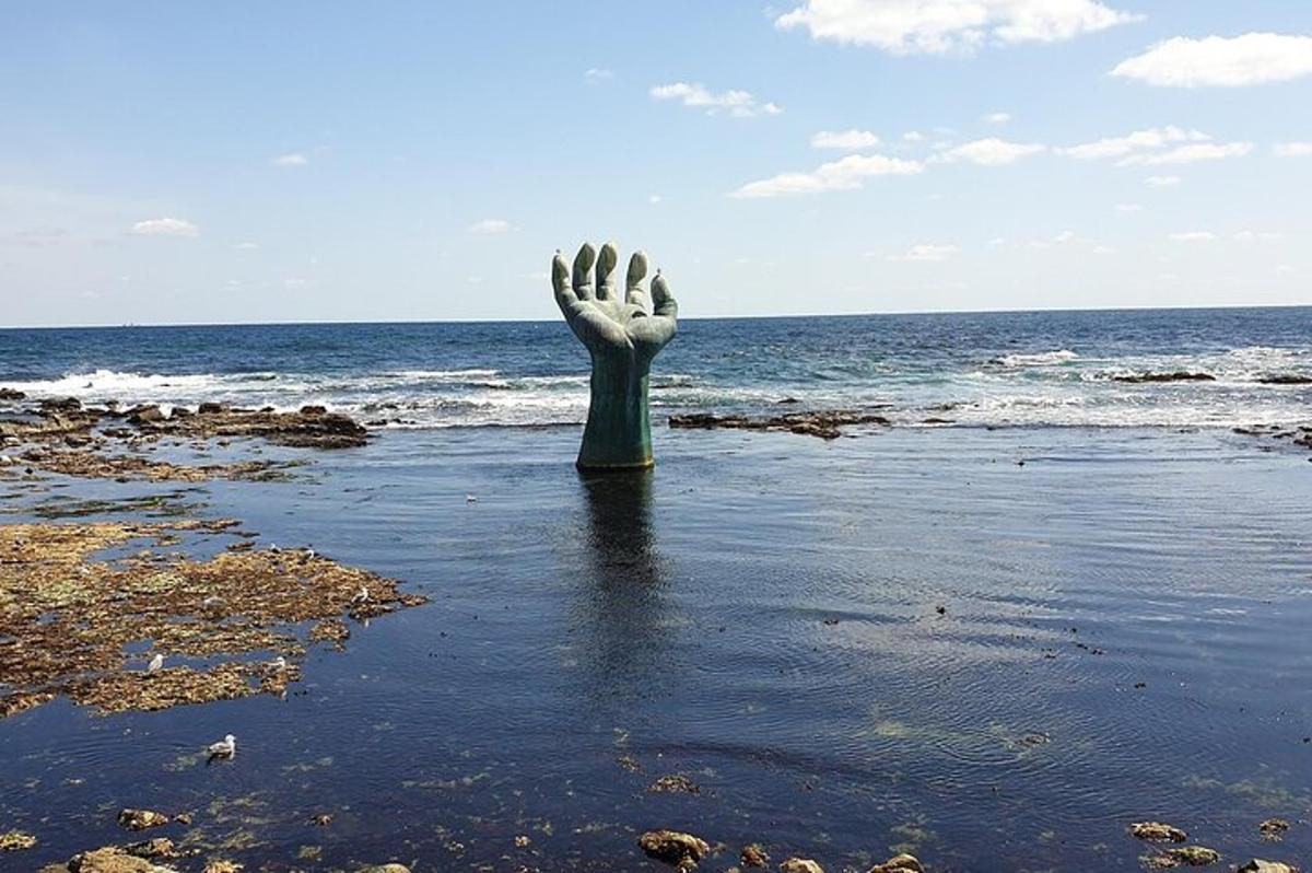 eine Statue einer Hand im Wasser in der Nähe des Ozeans