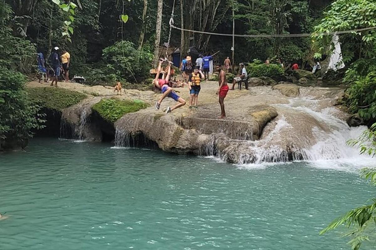 a group of people playing in the water near a waterfall
