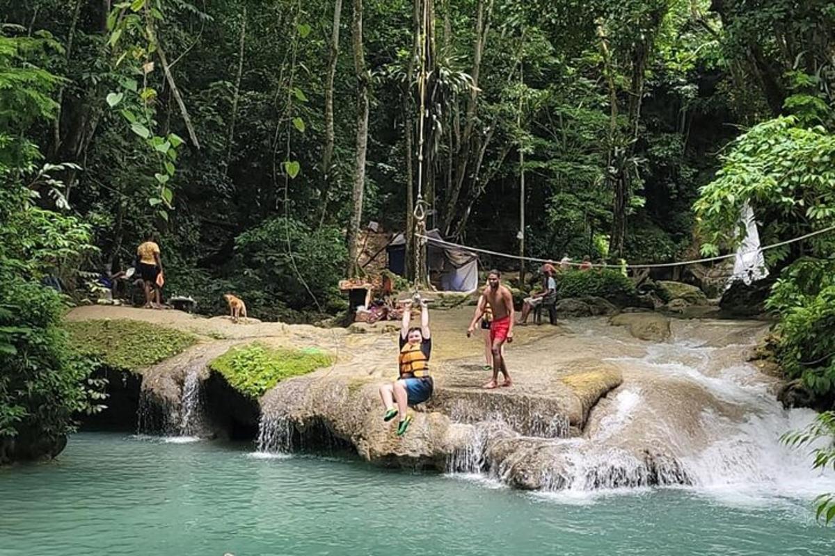sekumpulan orang berdiri di dalam air berhampiran air terjun