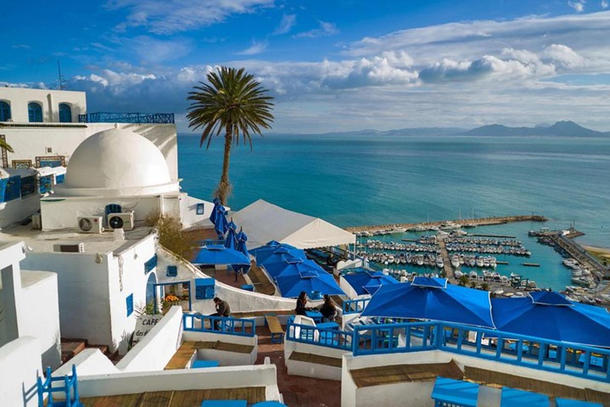 a view of a resort with blue umbrellas and the ocean